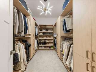 Step into this impeccably organized walk-in closet, featuring custom built-in shelving and ample hanging space for a sophisticated wardrobe.