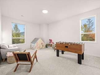 This bright and airy playroom is perfect for family fun, featuring a classic foosball table and a cozy reading nook with a plush sofa and a charming play tent.