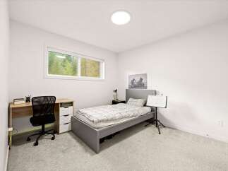 This modern bedroom features a comfortable single bed with a stylish grey frame and a patterned duvet.