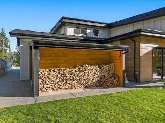 This modern home features a stylish outdoor wood storage shed, perfect for keeping firewood dry and accessible.