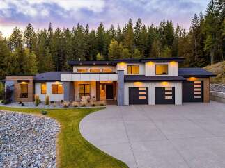 Experience modern luxury in this stunning contemporary home, nestled against a backdrop of lush evergreen trees.