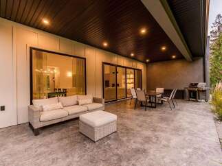 Enjoy seamless indoor-outdoor living with this stunning covered patio, featuring a comfortable sectional sofa and ottoman perfect for relaxing.