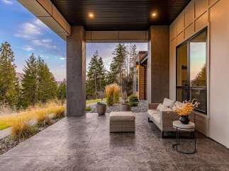 Experience luxurious outdoor living on this stunning covered patio, featuring comfortable wicker seating and a stylish ottoman.