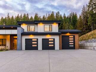 Discover modern luxury in this stunning multi-level home, featuring a sleek design with a mix of white siding and warm wood accents.