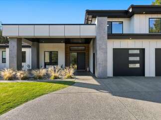 Experience modern luxury in this stunning home featuring a sleek facade with white vertical siding and dark accents.