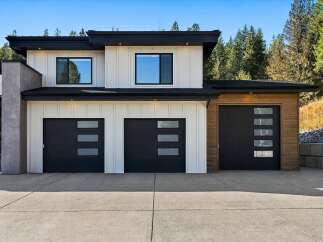 This modern home features a striking facade with a combination of white vertical siding and natural wood accents.