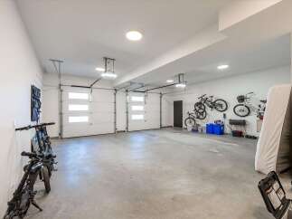 This spacious garage offers ample storage and parking with three overhead doors and a durable concrete floor.