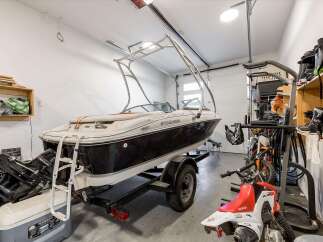 Store your boat and recreational vehicles in this spacious garage, complete with a boat on a trailer and multiple dirt bikes.