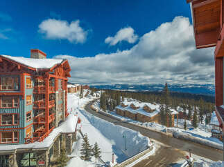 Experience luxury mountain living in this stunning ski resort property, featuring a vibrant teal and red exterior with ample balconies offering breathtaking views.