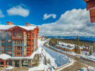 Experience luxury mountain living in this stunning ski resort property, featuring a vibrant blue and orange exterior with snow-capped roofs.