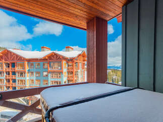 Experience the ultimate mountain getaway from this stunning balcony, complete with a snow-covered hot tub offering breathtaking views of the surrounding ski resort.