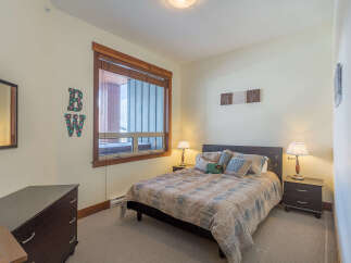 This cozy bedroom features a comfortable queen-size bed adorned with a patterned quilt and decorative pillows.