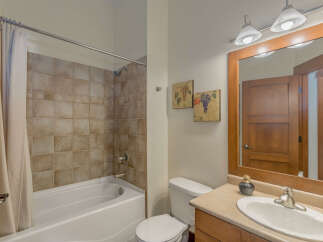 This bathroom features a classic design with a tiled shower and tub combination, complemented by a wooden vanity and a large mirror.