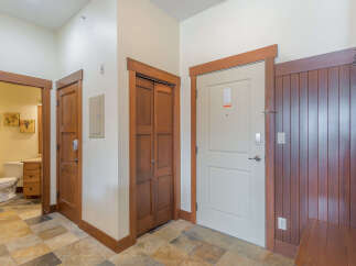 Step into this inviting entryway featuring a convenient closet and a well-appointed bathroom accessible through a charming wooden door.