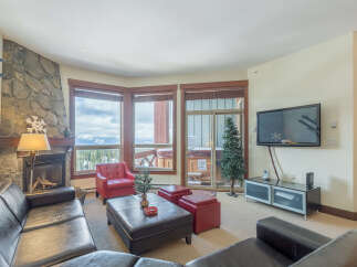 Experience cozy living in this mountain retreat, featuring a stone fireplace and large windows with stunning views.
