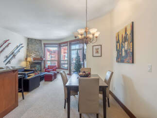Experience mountain living in this charming condo, featuring a cozy living area with a stone fireplace and a well-appointed dining space perfect for entertaining.