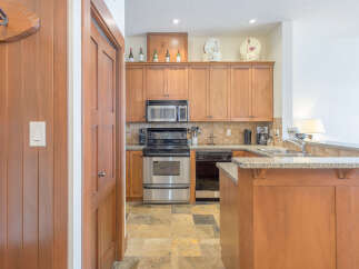This charming kitchen features warm wood cabinetry and sleek stainless steel appliances, including a built-in microwave and a modern oven.
