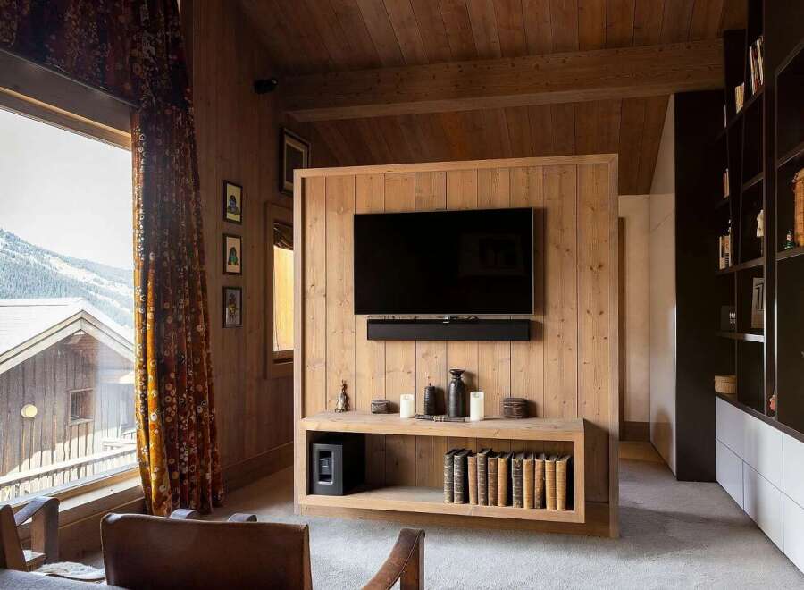 Experience luxury mountain living in this stunning wood-paneled living room, featuring a large television mounted above a sleek entertainment unit.