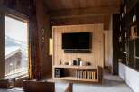 Experience luxury mountain living in this stunning wood-paneled living room, featuring a large television mounted above a sleek entertainment unit.