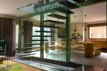 Experience modern luxury with this stunning staircase, featuring floating wooden steps encased in sleek glass walls.
