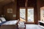 Experience breathtaking mountain views from this cozy bedroom, featuring warm wood paneling and large windows.