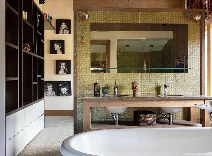 This rustic bathroom features a freestanding white bathtub as the centerpiece, complemented by a wooden vanity with double sinks and modern faucets.