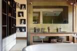 This rustic bathroom features a freestanding white bathtub as the centerpiece, complemented by a wooden vanity with double sinks and modern faucets.