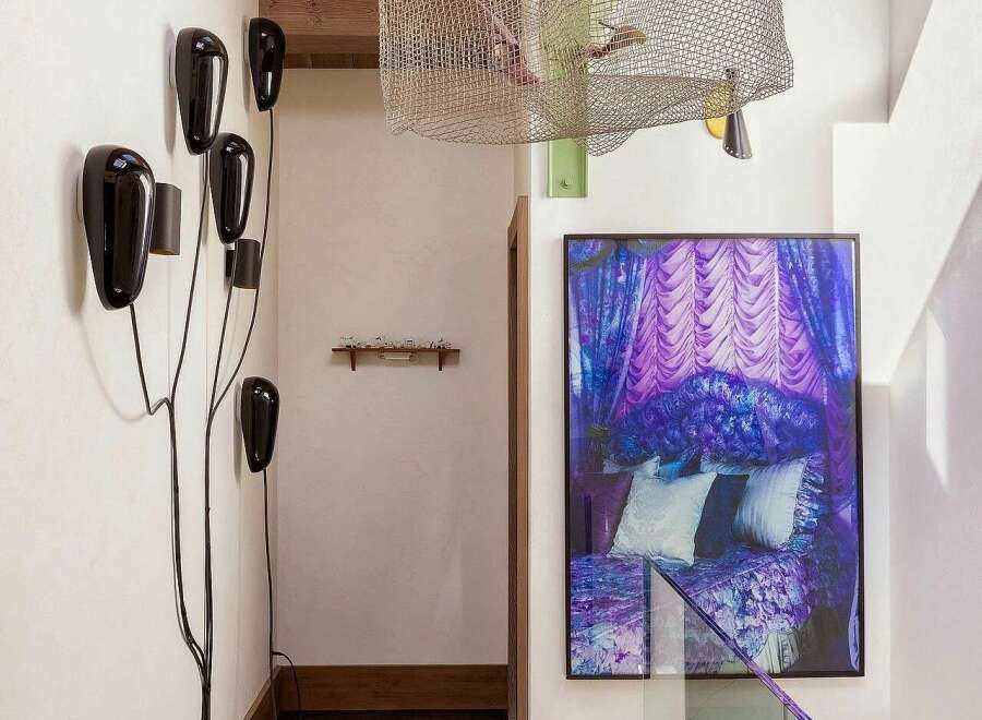 This hallway features a unique artistic flair with a striking purple abstract art piece and a sculptural wall-mounted light fixture.