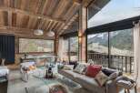 Experience luxurious mountain living in this stunning chalet, featuring a vaulted wood-beamed ceiling and expansive windows that frame breathtaking alpine views.