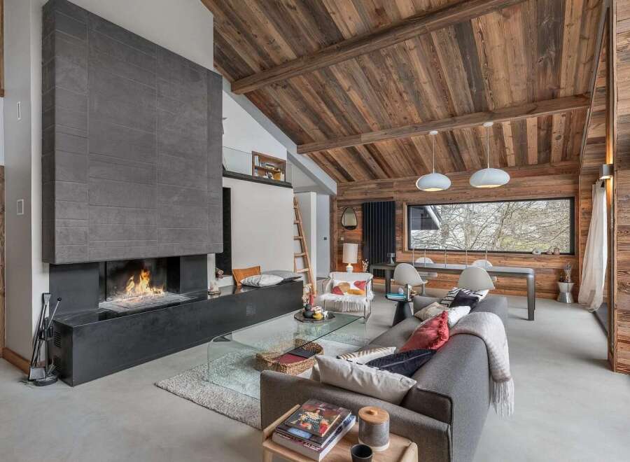 Experience luxury mountain living in this stunning chalet, featuring a grand stone fireplace and a vaulted wooden ceiling that exudes rustic charm.
