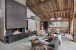 Experience luxury mountain living in this stunning chalet, featuring a grand stone fireplace and a vaulted wooden ceiling that exudes rustic charm.