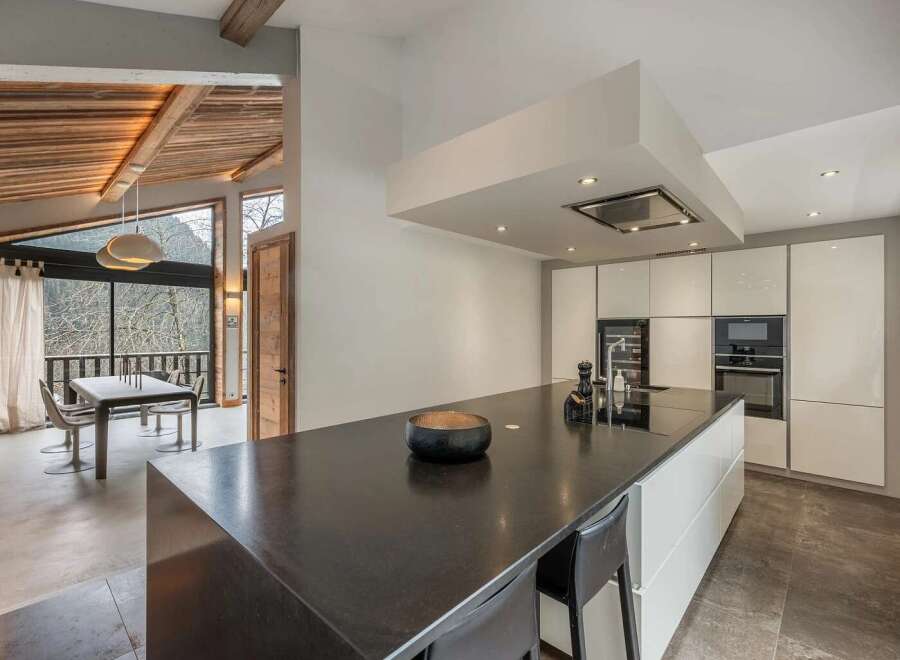 Experience modern luxury in this stunning open-plan kitchen and dining area, featuring sleek white cabinetry and a spacious dark stone island.