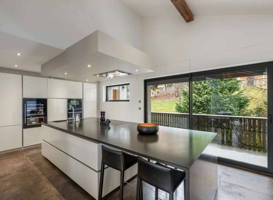 Experience modern luxury in this stunning kitchen, featuring sleek white cabinetry and a spacious dark stone island perfect for entertaining.