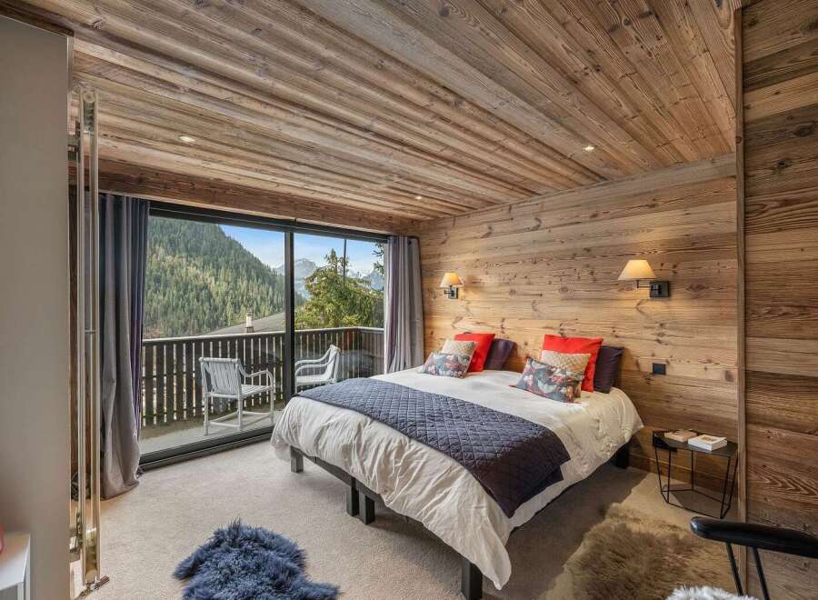 Experience luxury mountain living in this beautifully appointed bedroom featuring a cozy king-sized bed with plush bedding and decorative pillows.
