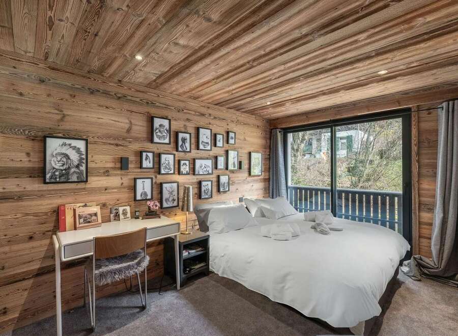 Experience rustic charm in this beautifully appointed bedroom, featuring warm wooden paneling on the walls and ceiling.