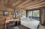 Experience rustic charm in this beautifully appointed bedroom, featuring warm wooden paneling on the walls and ceiling.