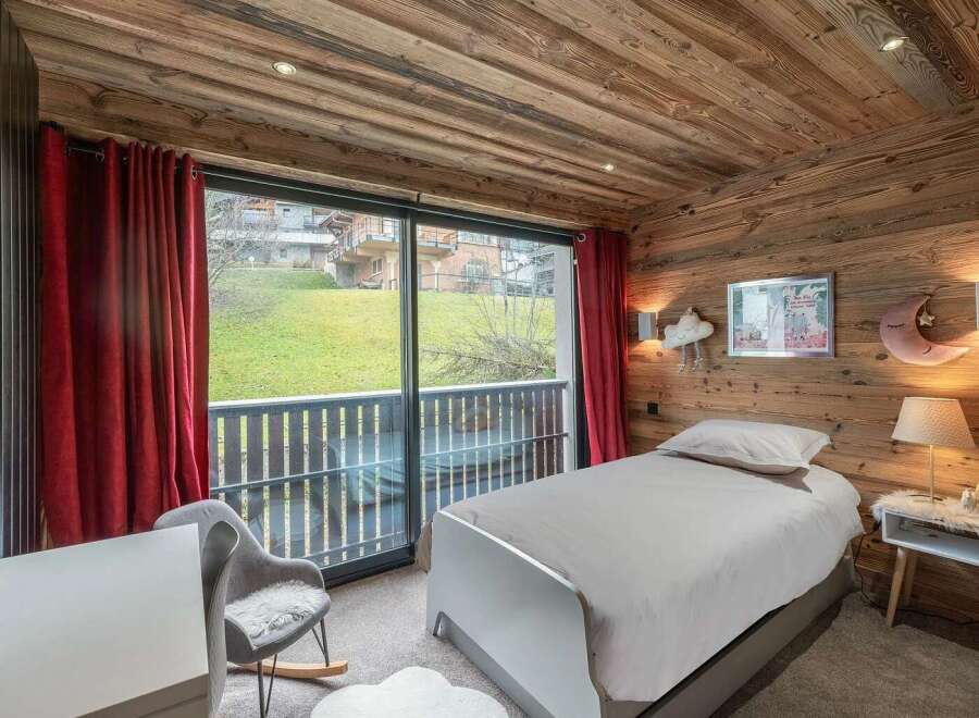 Experience cozy mountain living in this charming bedroom featuring rustic wooden walls and ceiling.