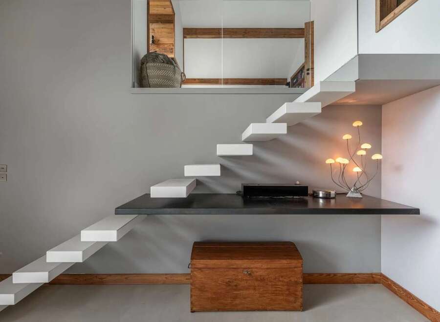 Discover a modern and minimalist living space featuring a unique floating staircase that leads to an upper level.