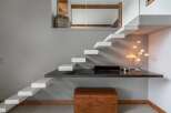 Discover a modern and minimalist living space featuring a unique floating staircase that leads to an upper level.