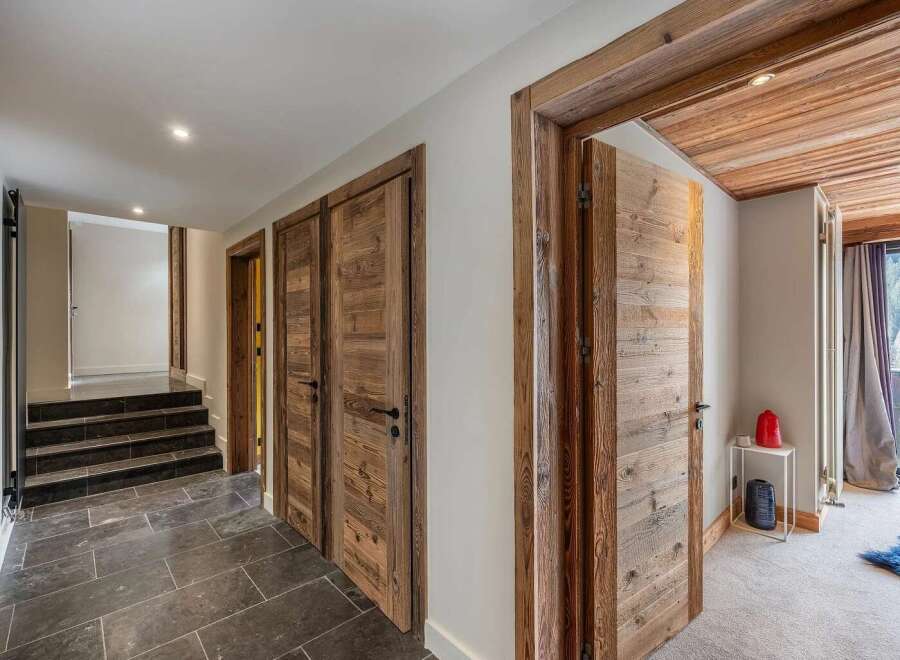 Step into a charming hallway featuring rustic wooden doors and a slate tile floor.