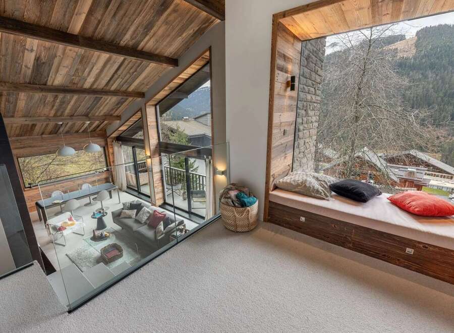 Experience breathtaking mountain views from this stunning chalet, featuring a vaulted wood-beamed ceiling and expansive windows.