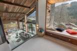 Experience breathtaking mountain views from this stunning chalet, featuring a vaulted wood-beamed ceiling and expansive windows.