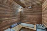 Experience ultimate relaxation in this luxurious wooden sauna, featuring a modern electric heater and a stack of hot stones.