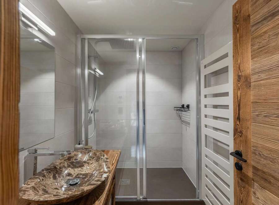 Experience modern luxury in this stunning bathroom featuring a unique marble vessel sink atop a rustic wooden vanity.