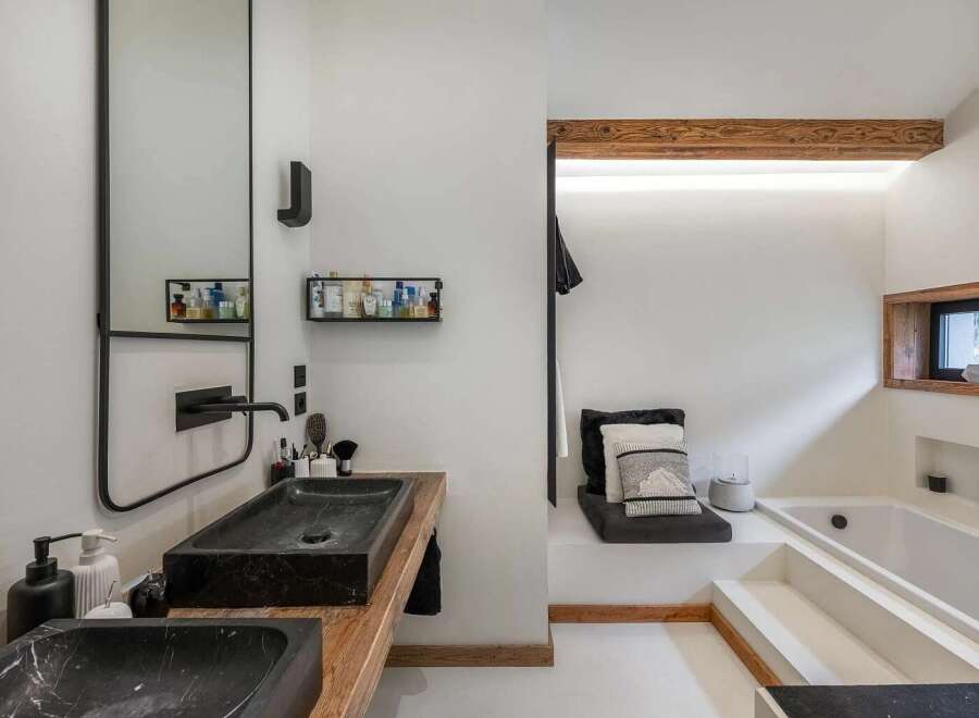 Experience modern luxury in this stunning bathroom featuring a sleek black marble double vanity with a wooden countertop.