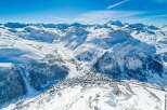 Discover this stunning aerial view of a picturesque village nestled in a snow-covered mountain valley.