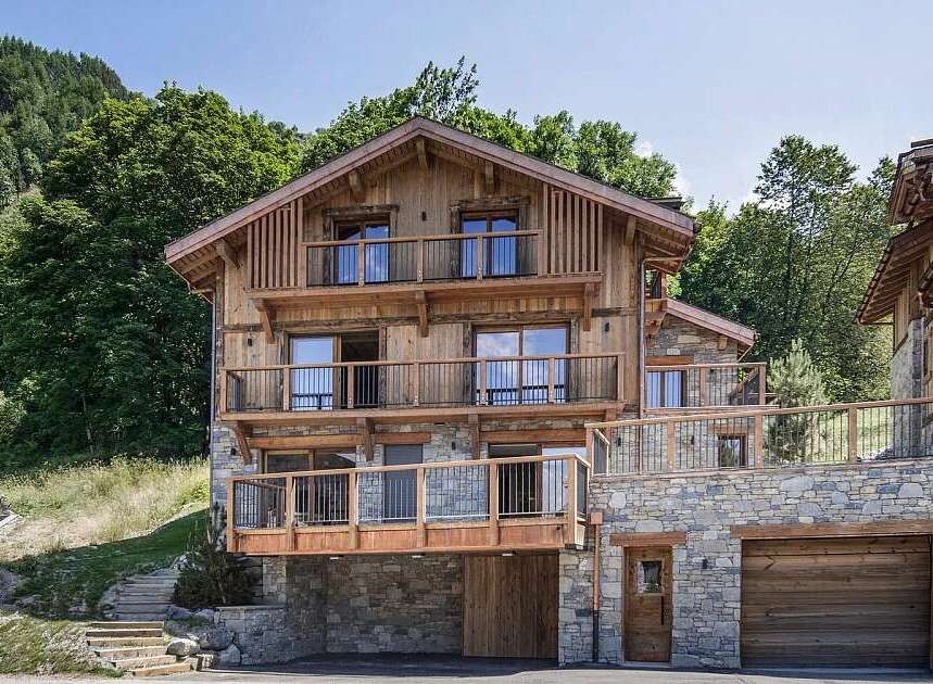 Experience luxury mountain living in this stunning chalet, featuring a multi-level design with extensive wooden and stone accents.