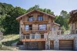 Experience luxury mountain living in this stunning chalet, featuring a multi-level design with extensive wooden and stone accents.