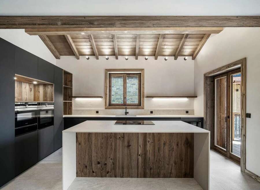 Experience rustic elegance in this modern kitchen, featuring a stunning wooden island with a sleek countertop and integrated stovetop.