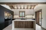 Experience rustic elegance in this modern kitchen, featuring a stunning wooden island with a sleek countertop and integrated stovetop.